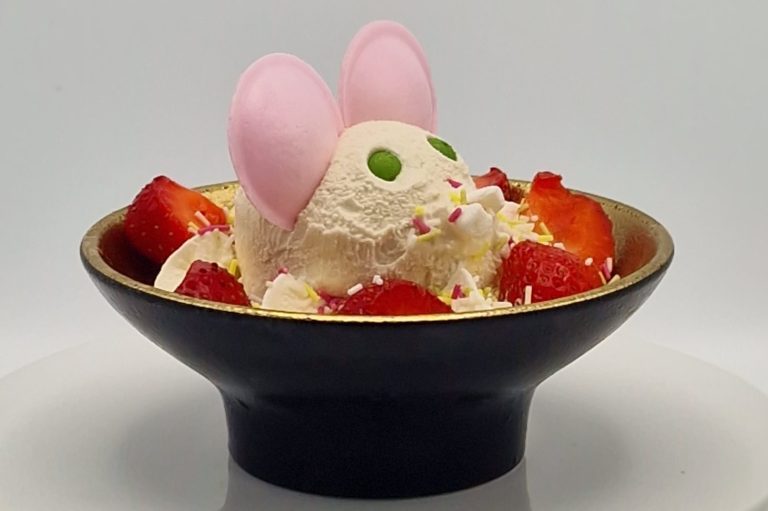 Eiskugel in einer Schale, dekoriert mit Erdbeeren und Zuckerstreuseln, mit Ohren aus Zucker.