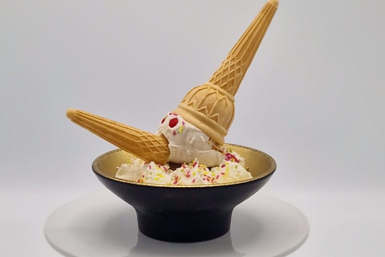 Eisdessert in einer Schale mit zwei Waffelhörnern und bunten Streuseln.